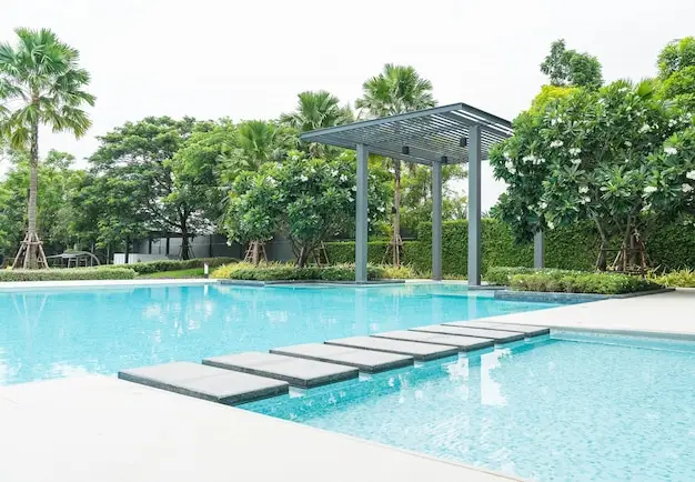 Pool with stepping stones, shaded pergola, and tropical greenery.